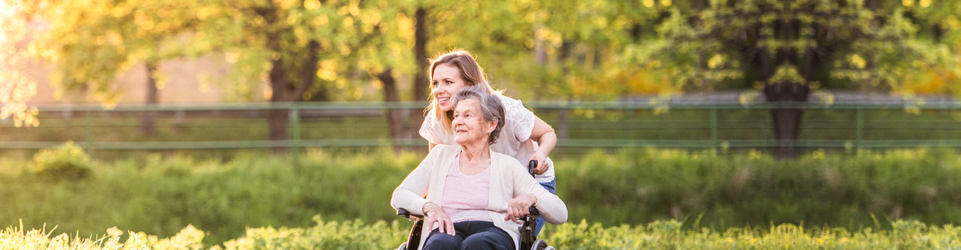 a woman smiling while holding an elderly woman sitting on the wheelchair