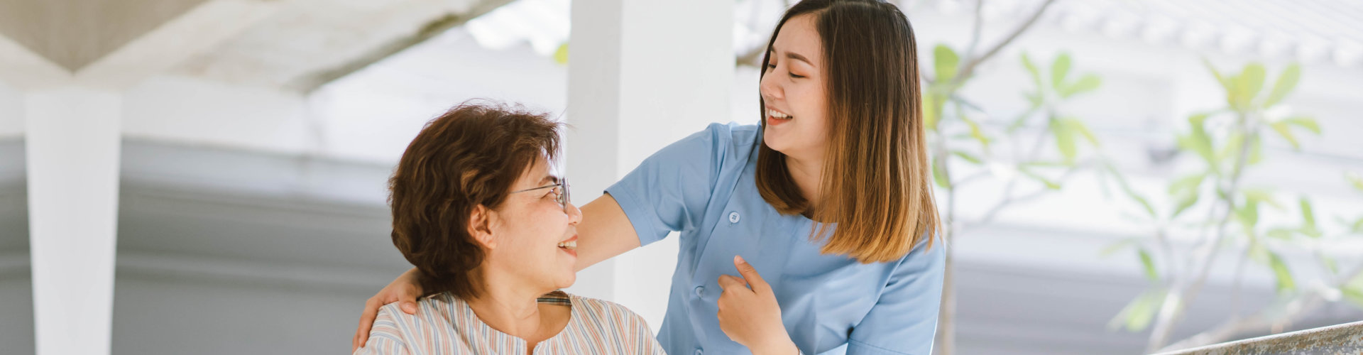 caregiver smiling to a elderly woman on a wheelchair